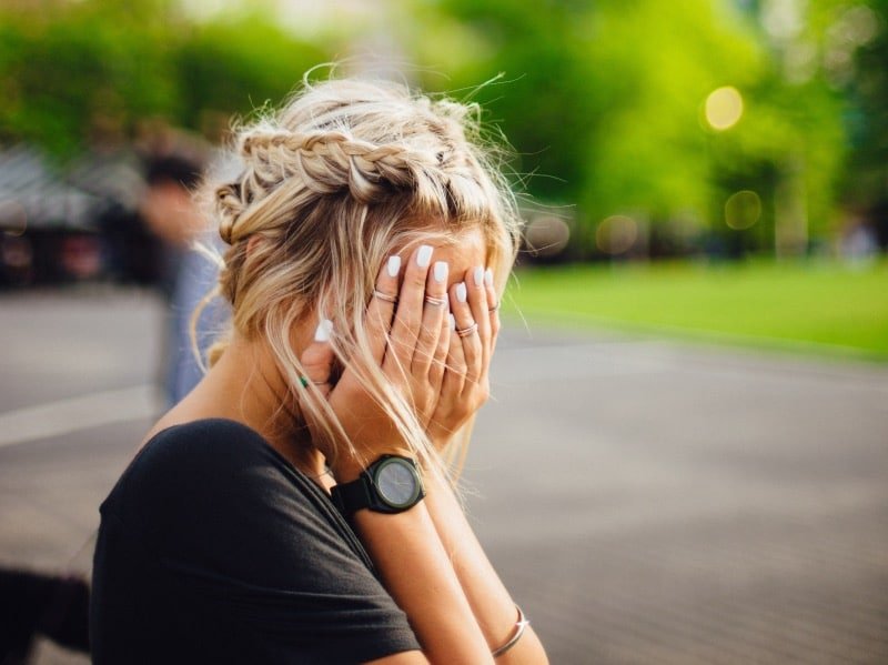 Hoog cortisolgehalte: Vrouw zit met handen voor gezicht