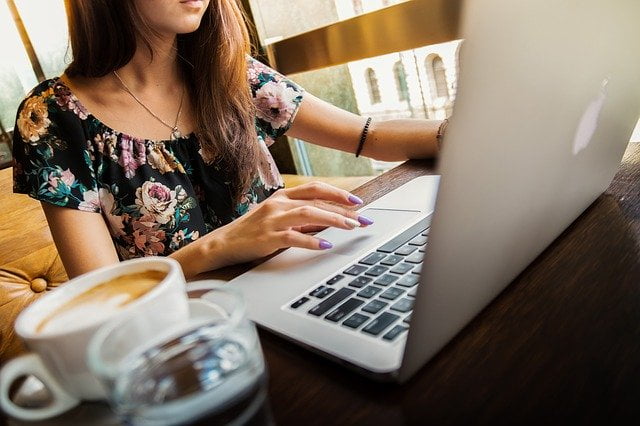 Vrouw achter laptop met koffie