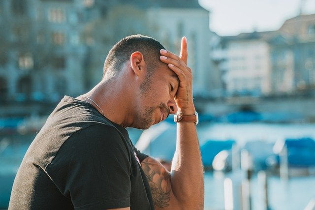 Jonge man met hoofdpijn en hand op voorhoofd