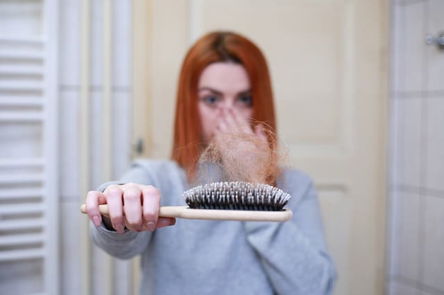 Vrouw met borstel met haar in haar hand