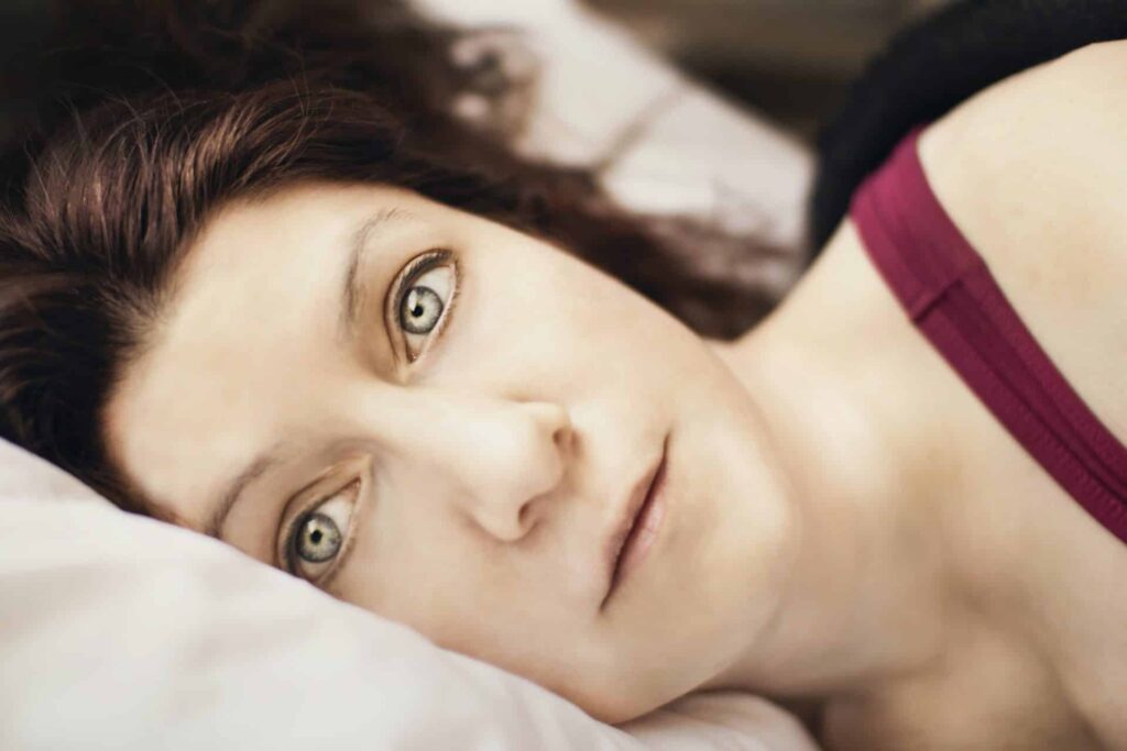 Vrouw ligt met ogen wijd open in bed en kan niet slapen