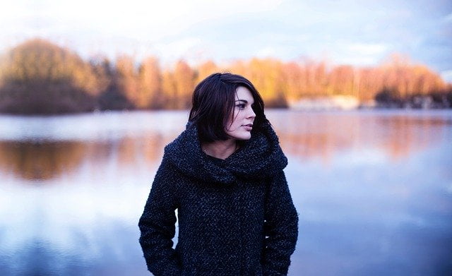 Vrouw staat in de natuur en worstelt met negatieve gedachtes